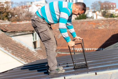 Roofer çatıda metal levha monte eder. İnşaat işçileri - yeni çatı montajı. Çatı araçları.