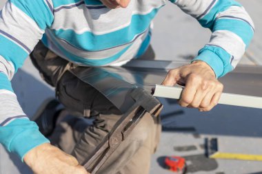 Roofer çatıda metal levha monte eder. İnşaat işçileri - yeni çatı montajı. Çatı araçları.