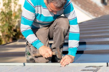 Roofer çatıda metal levha monte eder. İnşaat işçileri - yeni çatı montajı. 