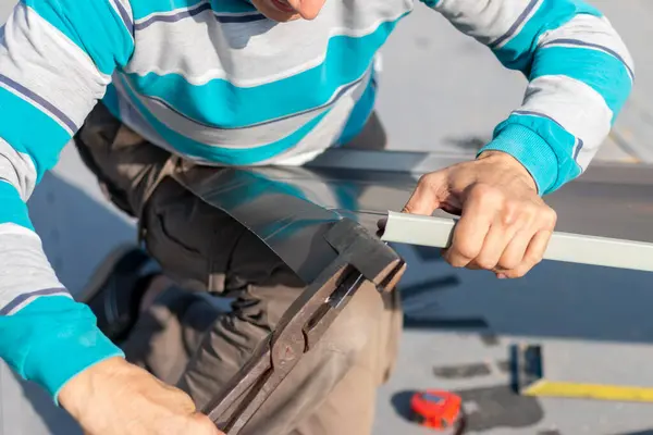 Roofer çatıda metal levha monte eder. İnşaat işçileri - yeni çatı montajı. Çatı araçları.