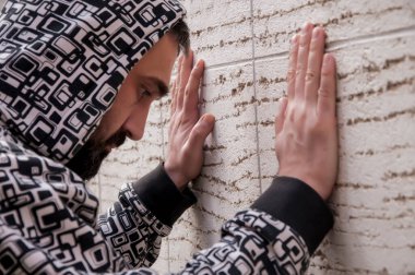 Anksiyete muzdarip genç depresif adam ve sefil duygu elleri ile yüzünü kaplayın ve duvara yaslanmış ağlamak