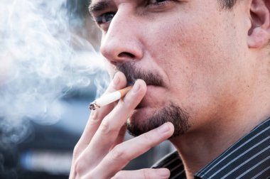 Şehir caddesinde sigara içen yakışıklı genç sakallı adamın portresi