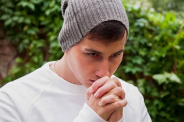 Parkta genç yakışıklı adam Tanrı'ya dua ediyor. İnanç, maneviyat ve din kavramı.