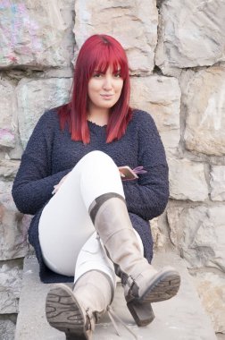 Duvarın yanında oturan kırmızı saçlı genç, çekici uzun saçlı bir kadının portresi