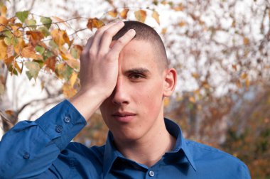 Parkta başını tutarak baş ağrısı ile yakışıklı genç genç