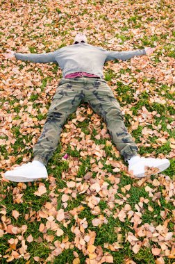 Parktaki düşen yapraklarla kaplı yerde yatan yakışıklı genç