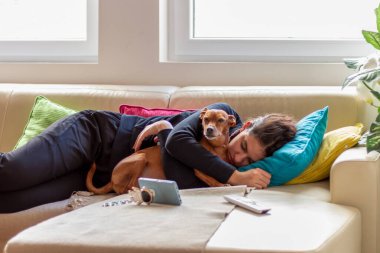 Yatakta pinscher cinsine sarılan tatlı bir genç kız. Bir genç yatakta uyuyor ve sevgili köpeğine sarılıyor.. 