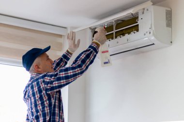 Bir teknisyen hava durumu birimini temizler ve korur. Solunum hastalığını önlemek için sağlık hizmeti ve bakım, havalandırma ünitesini tamir etmek ve filtreleri temizlemek / dezenfekte etmek.