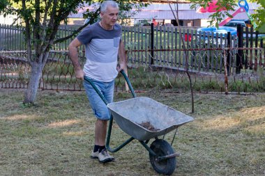 Bahçedeki çimlerle ilgilenen olgun bir adam. Tarım, bahçe ekipmanları konsepti