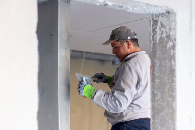 Duvarları sıvayan bir usta. Duvara alçı yapıştırma işlemi. Evin yenilenmesi ve yenilenmesi konsepti