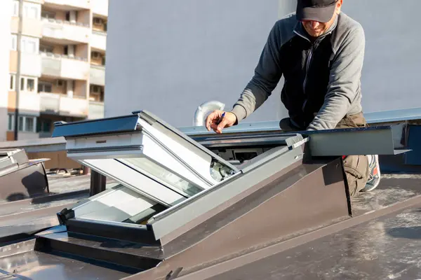 Çatı ustası ve pencere ustası. Zanaatkar tavan penceresini metal levha ile kaplıyor. Çatı araçları.