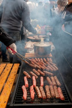 Metal maşanın yardımıyla erkekler ızgarada haşlanan kebapları ve hamburgerleri çeviriyor. Yiyecek ve içecek yaşam tarzı konsepti