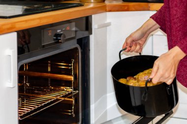 A woman put a baking traditional dish in the oven in the kitchen. The joy of cooking delicious meals. clipart