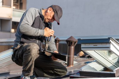 Roofer yeni bir çatı penceresi kuruyor. Bir çatı örtüsü parçası olarak yeni çatı pencerelerinin kurulumu ve montajı