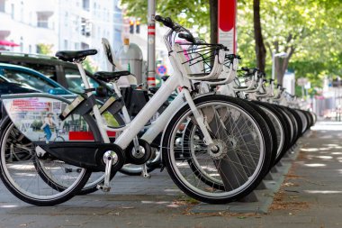 Caddedeki şehir merkezindeki otoparkta kiralık elektrikli bisikletler yeşildir. Çevre dostu ulaşım aracı. Kiralık bisiklet, park yerinde tekerlek sayısı.