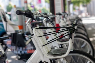 Caddedeki şehir merkezindeki otoparkta kiralık elektrikli bisikletler yeşildir. Çevre dostu ulaşım aracı. Gidon kısmında seçici odak ile yakın çekim.