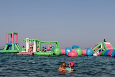Ormos Panagias, Yunanistan, 5 Ağustos. 2023: Şişme zıplayan kale Ege Denizi 'nin dalgaları üzerinde sürükleniyor. Deniz manzaralı bir su parkı. Popüler turizm aktiviteleri, su sporları