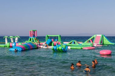 Ormos Panagias, Yunanistan, 5 Ağustos. 2023: Şişme zıplayan kale Ege Denizi 'nin dalgaları üzerinde sürükleniyor. Deniz manzaralı bir su parkı. Popüler turizm aktiviteleri, su sporları