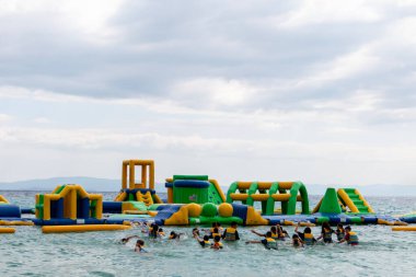 Ormos Panagias, Yunanistan, 28 Temmuz. 2023: Şişme zıplayan kale Ege Denizi 'nin dalgaları üzerinde sürükleniyor. Deniz manzaralı deniz manzaralı bir su parkı. Popüler turizm aktiviteleri, su sporları.