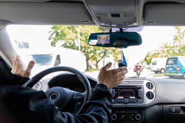 Angry young  man pissed off by drivers in front of him and gesturing with hands. Concept of road rage and stress.