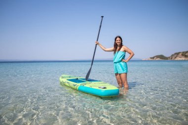 Yemek bordası. Denizin arka planında yemek tahtası olan çekici bir genç kız. Aktif yaşam tarzı ve sörf kavramı.