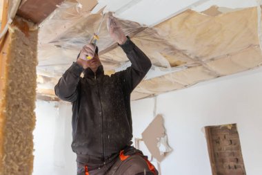 Olgun bir adam evin tadilatında çalışıyor. Ev tadilatında çalışan gerçek bir inşaat işçisi. Gerçek bir iş adamı. Ev geliştirme konsepti.