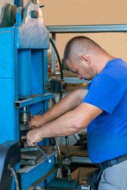 Araba tamircisi bir atölyede hidrolik zemin presi üzerinde çalışıyor. Etkili metal oluşumu ve şekli için tasarlanmış dayanıklı hidrolik baskı