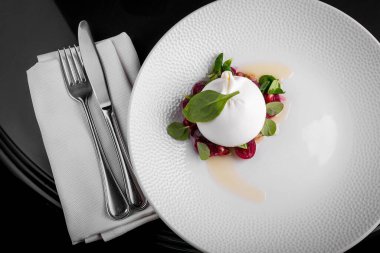 Italian dish burrata cheese with basil leaves and olive oil on a white plate. Vegetarian food