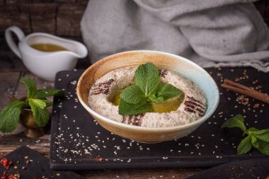 delicious classic traditional arabic hummus with olive oil and mint leaves on black board 