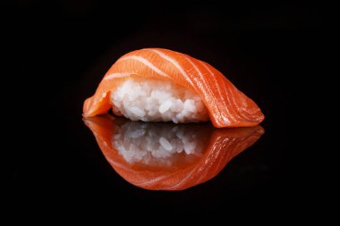 classic sushi with salmon on a black background with reflection 