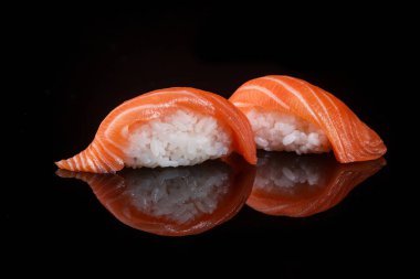 classic sushi with salmon on a black background with reflection 