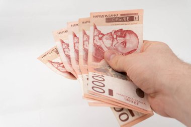 Elinde yığınla para tutan adam. Beyaz arka planda izole edilmiş 5000 RSD Sırp Dinar banknot kağıt para birimi.
