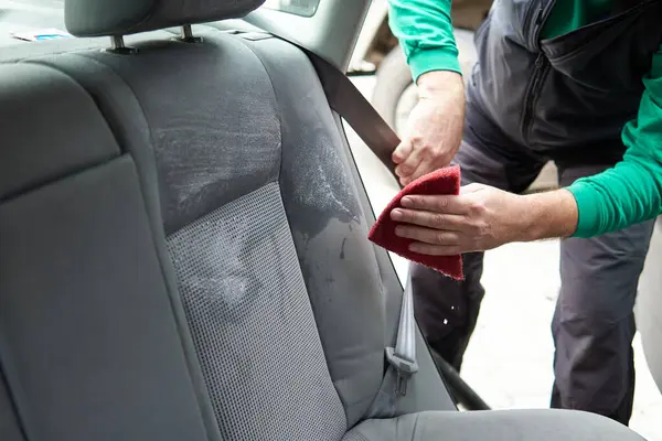 Car cleaning detailing - male using professional steam vacuum chemical cleaning for dirty car interior seats with extraction method