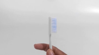 Beyaz arka planda izole edilmiş yeni bir diş fırçasını tutan bir adamın yakın çekimi. Bir diş fırçasını döndürmenin video illüstrasyonu