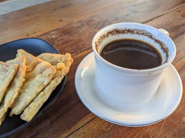 Beyaz seramik kahve ve kızarmış Tempeh veya ahşap masada Tempeh Mendoan..