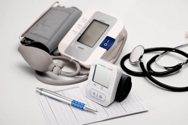 stock image Tonometers, brachial and automatic digital wrist sphygmomanometer, stethoscope, lie on the table, pressure diagnostics, on a white background