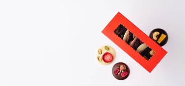 Ev yapımı kırmızı kutuda çikolatalı şekerler, beyaz arka planda, pankartta, metin için yer