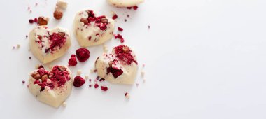 Kalp şeklinde çikolatalı şekerler, çilekli sütlü çikolata, yabanmersini ve badem, el yapımı, üst görünüm, beyaz arka plan, afiş, yazı için yer