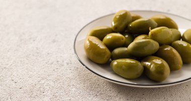 Tabakta büyük yeşil zeytinler, açık arkaplan, metin için yer