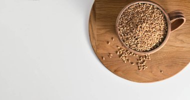 Cereal for cooking, whole wheat grain, in a cup on a white background, top view, place for text