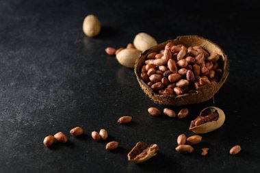 Fıstıklar, kuru fıstıklar, fındıklar Hindistan cevizi kasesinde koyu gri arka planda.