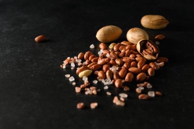 yer fıstığı, kuru yer fıstığı, ceviz, Himalaya kaba tuzu koyu gri arka planda, mesaj için boş alan