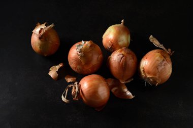 Soğanlar kuru, olgun, siyah arka planda bir grup halinde, yakın plan.