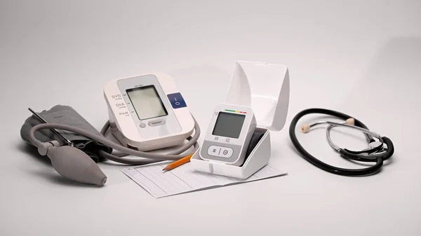 自動デジタル手首と胸血圧モニター 圧力監視チャート 白い背景に聴診器メガネ — ストック写真