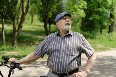 Olumlu, karizmatik yaşlı bir adam eko scooterla parkta yürüyüşe çıktı. Yaşlıların sağlıklı yaşam tarzı.