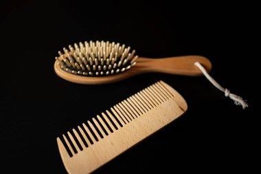 Wooden hairbrush and comb set on dark background with focus on texture and design features