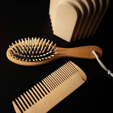 Wooden hairbrush and comb set on a dark surface with a stylish organizer nearby