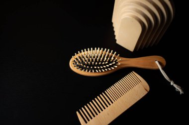 Wooden hairbrush and comb arranged on a dark table with modern sculptural objects