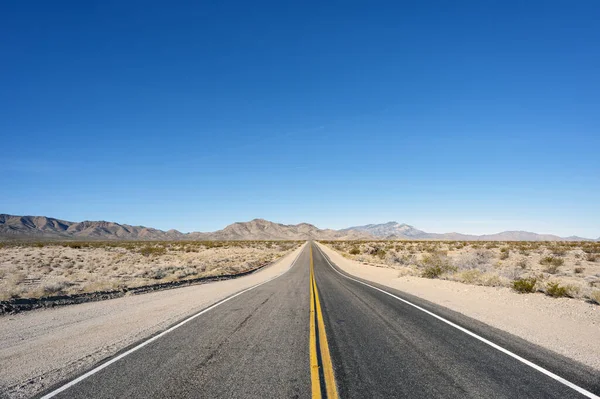 Empty road in desert with clear blue sky