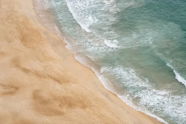 Aerial view of deserted sandy beach with people walking